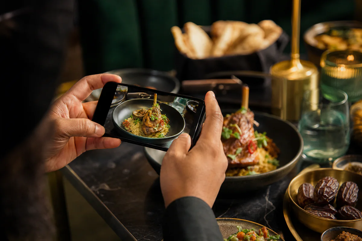 A creator capturing an artfully plated halal meal on a smartphone